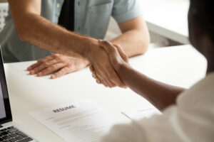 Handshake over the top of a table with a resume on it