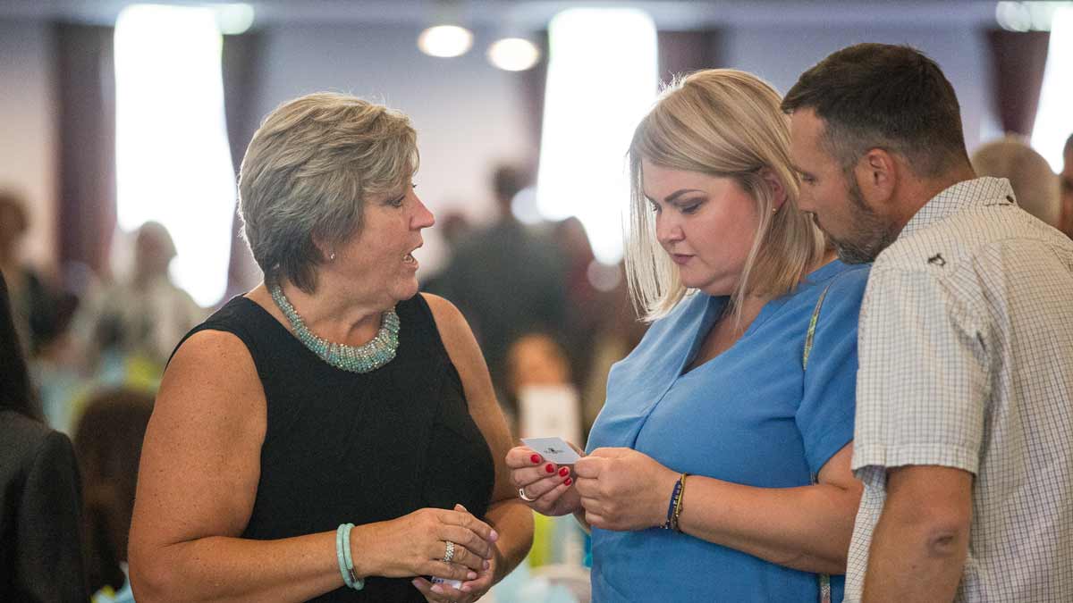 three people at a networking event with one looking at a business card