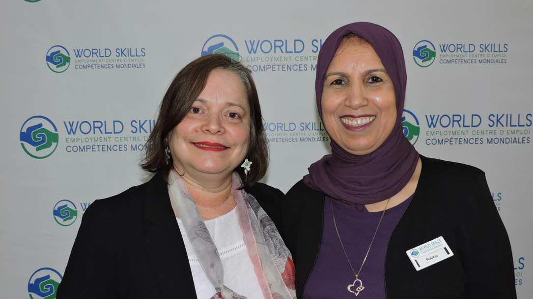 Two World Skills staff smiling in a head shot at an event 